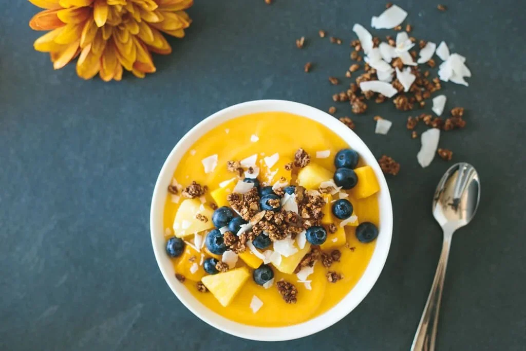 Bol de smoothie à la mangue avec des fruits frais et des garnitures