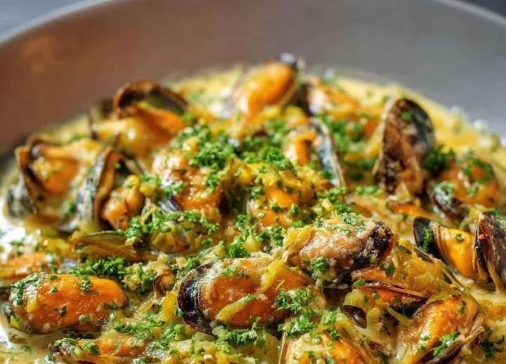 Fricassée de moules au poireau servie dans une assiette.